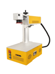 A yellow and white laser marking machine, viewed from a slightly elevated angle, is positioned against a clean white background. The machine's base is a rectangular yellow box with various buttons and vents on its front and sides. A silver vertical column rises from the base, supporting a horizontal arm that houses the laser components. The laser arm is primarily white with yellow accents and features a lens at its front, highlighted by a red ring. A black cable extends from the back of the laser arm. The overall design is compact and industrial.